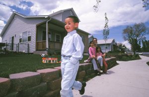 Four-year-old Anass Maimen walks down Benton Street in Denver, Colorado. The Habitat house behind him belongs to the Cruz family, pictured sitting on the retaining wall. (2001)