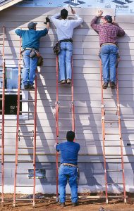 Volunteers Kenneth Batson, Kenneth Whigham, Ron Fritz, and David Skinner, all from McDonough, Georgia, hang vinyl siding on a Habitat house. (2002)