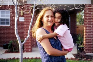 Habitat homeowner Blanca Gonzalez and her daughter Yaneli are pictured in front of their Habitat house in Greenleaf Village. Once completed, Greenleaf Village will be a 310-house community of mixed-income families, including 100 houses built by Dallas Area Habitat for Humanity. (2003)