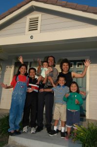 Habitat homeowner family Barbara and Alfonso Pelaez in front of their Habitat house.  The family was featured in one of the PSAs released by Habitat in 2004.  -Barbara and Alfonso immigrated to the US from Mexico. -They have five young children (although only four are in the PSA - the fifth is a little baby just born) -Alfonso works two jobs, one of which is at the Habitat affiliate Restore -According to friends and Habitat staff, Barbara and Alfonso are hard workers and excellent parents. -Before moving into their Habitat house, the Pelaez family lived in a very dangerous environment.  There was lots of drug dealing and on-going gang activity.  The smell of sewage and cigarette smoke filled their tiny apartment.  They lived in a three room apartment (one bedroom, a living room and small kitchen).  The children slept in the bedroom and the parents slept in the living room.   The apartment had many problems  including rotten windows and holes in walls. -The new Habitat home is spacious and located in a quiet & safe neighborhood with three other Habitat homes. The parents say the Habitat home provides a much healthier and safer environment for their children.  The children ride their bikes outside and now have plenty of room inside to study. -The family has shown tremendous pride in their home, planting beautiful flowers and plants around the home.