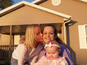 Habitat homeowner Mary Gallagher and family  in front of their Habitat house.  The family was featured in one of the PSAs released by Habitat in 2004.  -Mary is a 25-year old single mother of three (her son is disabled), who also cares for her 16-year old sister -Mary works night shift at a company putting together circuit boards. -Before moving into her Habitat home, Mary and her family were cramped in a roach infested two-bedroom apartment with a total of eight people (three others in addition to her family).  Mary experienced abusive relationships and had little hope. -Quote from a letter Mary wrote to the Fullers: "Habitat has truly healed my family as it has so many others.  Not only has Habitat helped me gain a beautiful new home, but also a brighter, healthier future for my children." "Thank you so much for your kind and loving hearts.  Without people like you, my family would still be lost in the crowd." -Mary lives in a beautiful home in a large Habitat neighborhood (about 50 homes in the neighborhood) -College students helped build her home. (2004)